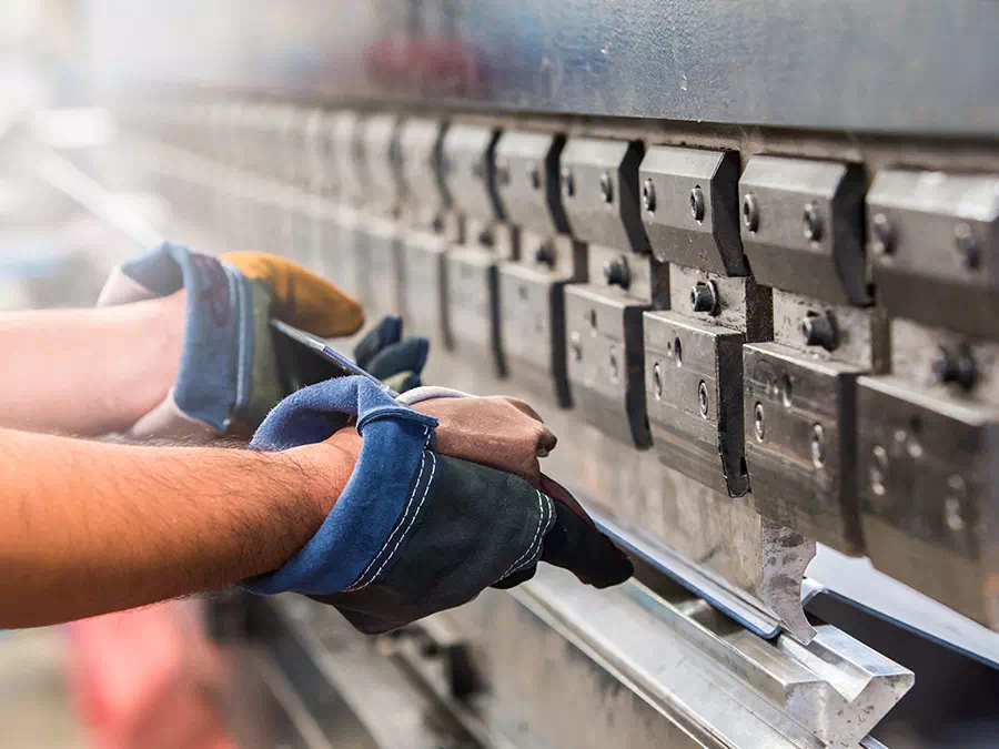 Operaio inserisce lamiera dentro pressa piegatrice Verona