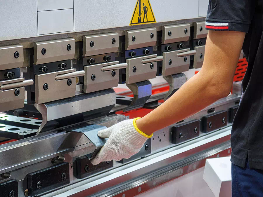 Operaio lavora pezzo di metallo medio in una pressa piegatrice Brescia