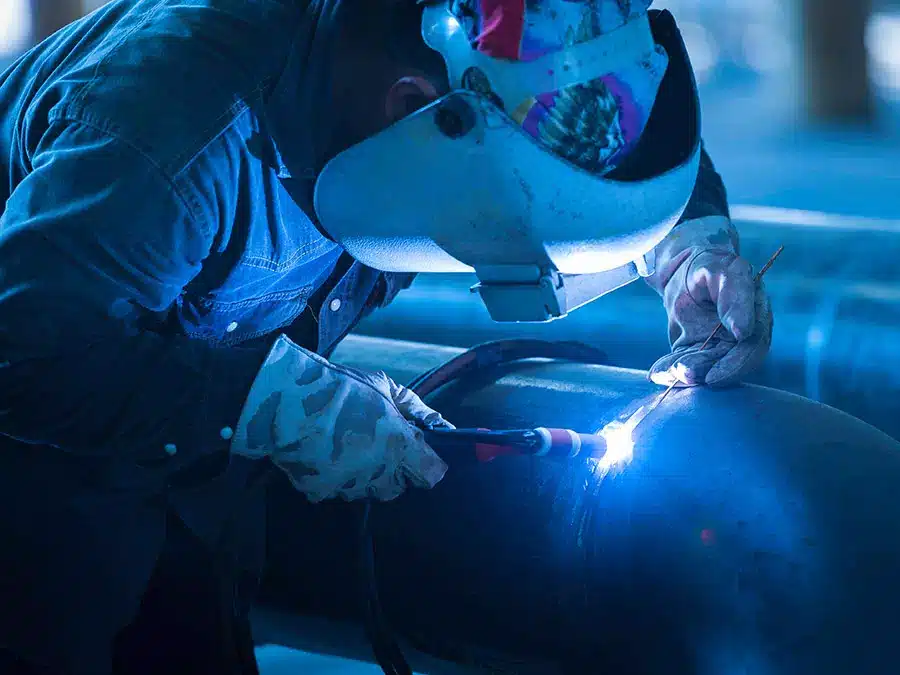 Operaio usa macchinario per saldatura su tubo di acciaio Brescia