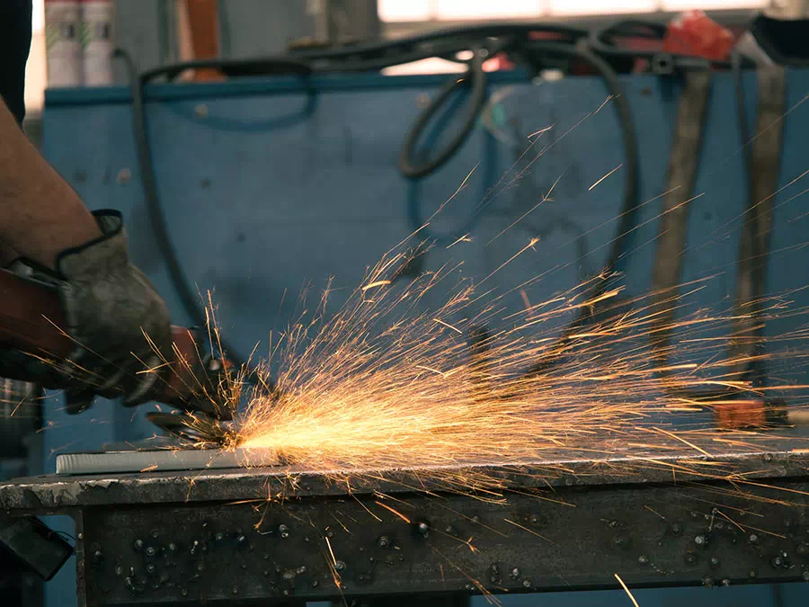 Operatore usa smerigliatrice per rifinire un componente metallico Mantova